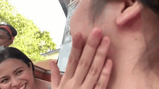 a woman is touching a man 's face with her hands while a man looks on .