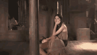 a woman is sitting on a man 's shoulders in a dark room .