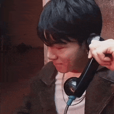 a man is talking on a telephone while covering his face .