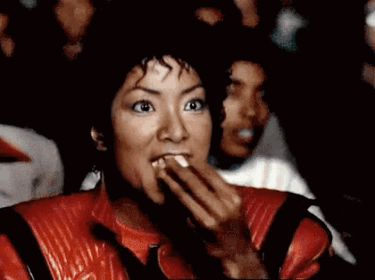 a woman in a red leather jacket is eating a piece of food .
