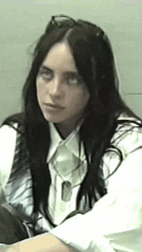 a woman with long black hair is wearing a white shirt and a white vest .