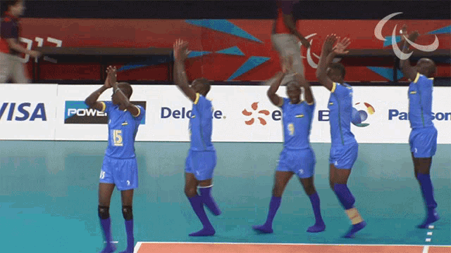 a group of volleyball players are clapping in front of a visa and delo logo