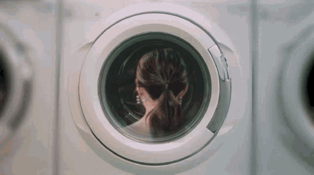 a woman looks out of a washing machine door