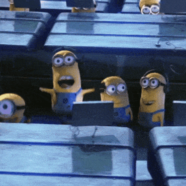 a group of minions wearing headphones are sitting in front of a computer