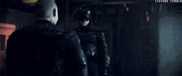 a couple of men are standing next to each other in a dark room and fighting .