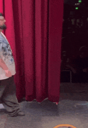 a man is standing in front of a red curtain in a theater .