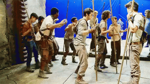 a group of young men are standing in a line holding sticks .