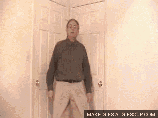 a man in a shirt and khaki pants is standing in a room .