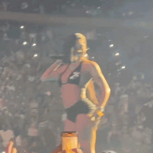 a woman in a bikini is dancing in front of a crowd of people .
