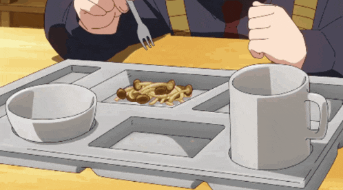 a person is sitting at a table with a tray of food and two cups