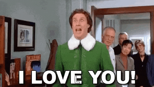 a man in a green jacket is standing in front of a group of people and saying `` i love you ! ''