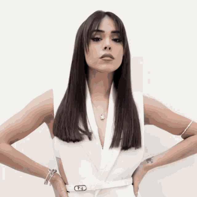 a woman wearing a white vest and a belt with the letter h on the buckle