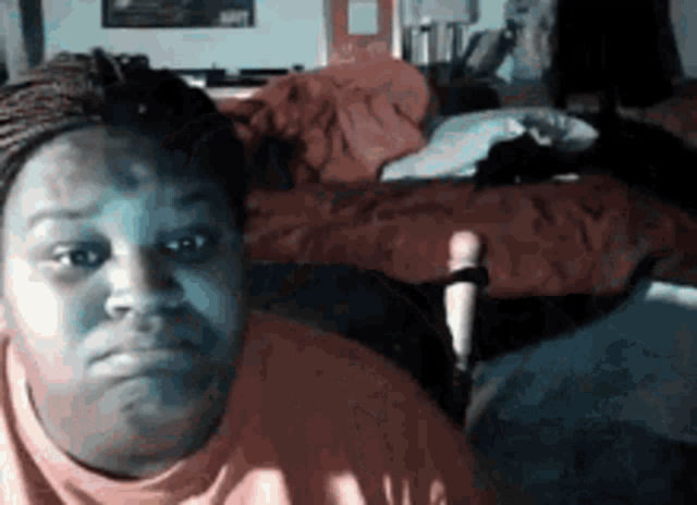 a woman is sitting in front of a bed and making a face