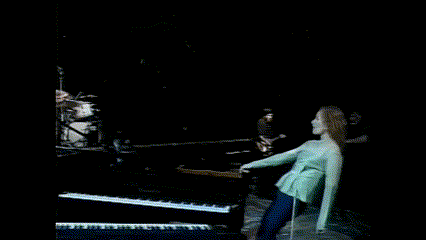 a woman is laying on the floor playing a piano in a dark room