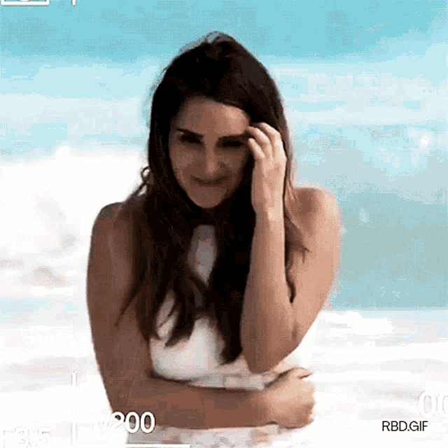 a woman is standing on a beach with a watermark that says rbd.gif