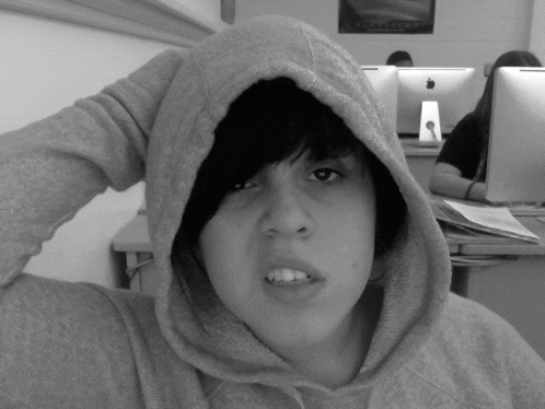 a black and white photo of a girl wearing a hooded sweatshirt