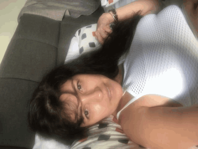 a woman in a white tank top is laying on her back