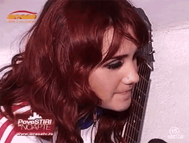 a woman with red hair is holding a guitar in front of a screen that says povestiri noapte