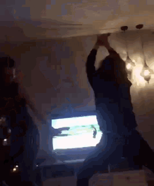 a group of people are dancing in a dark room in front of a television .