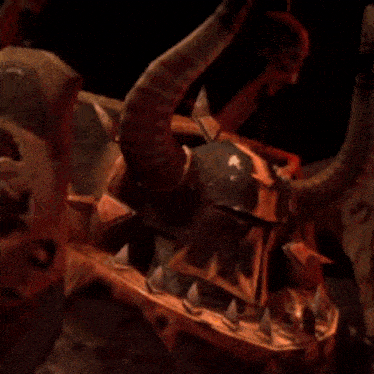 a close up of a demon with horns and a helmet