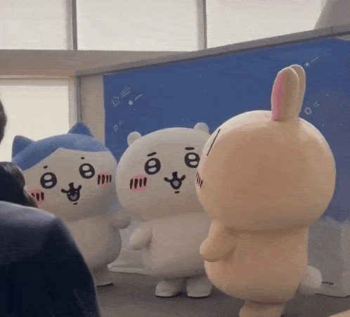 a group of stuffed animals including a cat and a bunny are standing next to each other