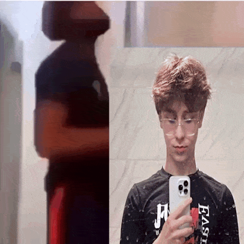 a young man taking a selfie in front of a mirror with a shirt that says east