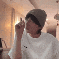 a man wearing a beanie and a white t-shirt is sitting in a room .
