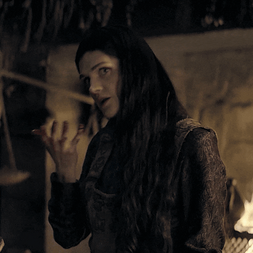 a woman with long black hair is covering her mouth with her hand