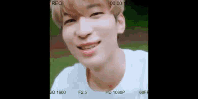 a young man is smiling for the camera while wearing a white t-shirt .