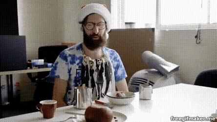 a man with a beard wearing a santa hat sits at a table with a bowl of food