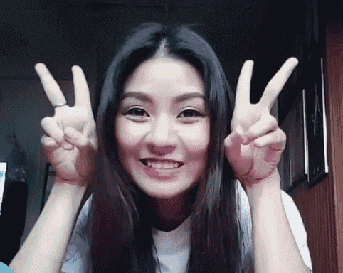 a young woman is giving a peace sign with both hands