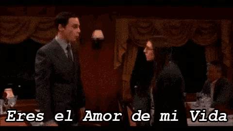 a man in a suit and tie stands next to a woman with the words eres el amor de mi vida written below them