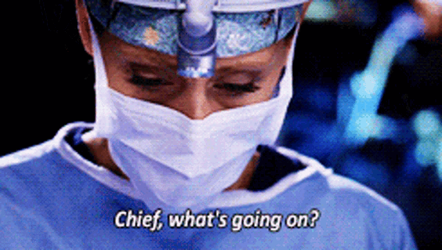 a surgeon wearing a mask and a head light says chief what 's going on