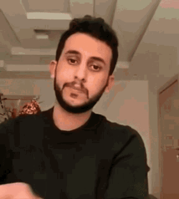 a man with a beard is making a funny face while sitting in a living room .