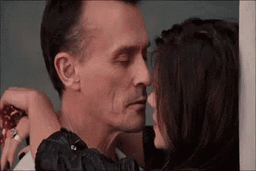 a man and a woman are kissing each other in a room .