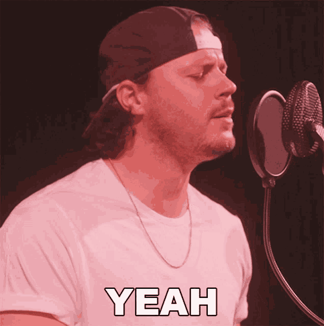 a man is singing into a microphone and the word yeah is on the shirt