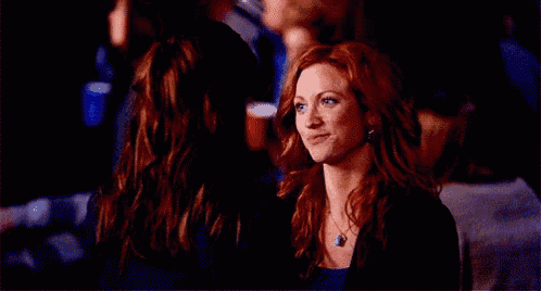 two women are sitting next to each other in a dark room and smiling .