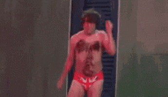 a man without a shirt is dancing in a locker room .