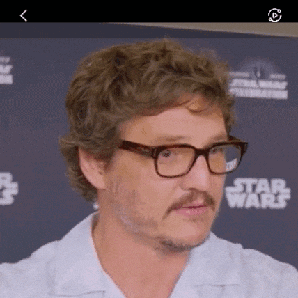 a man wearing glasses and a white shirt is standing in front of a star wars sign .