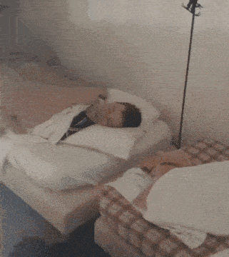 a young man is sleeping on a bed with a white pillow