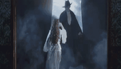 a man and a woman are standing in a dark room in front of a door .