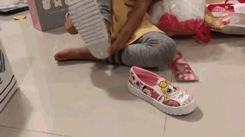 a little girl is sitting on the floor putting on a shoe