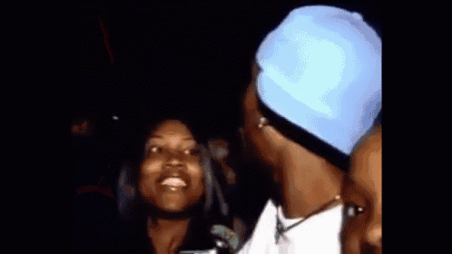 a man wearing a blue hat is singing into a microphone while standing next to a woman .