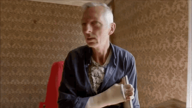 a man with a cast on his arm is sitting in a red chair