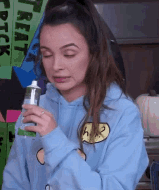 a girl in a blue hoodie is holding a tube of toothpaste