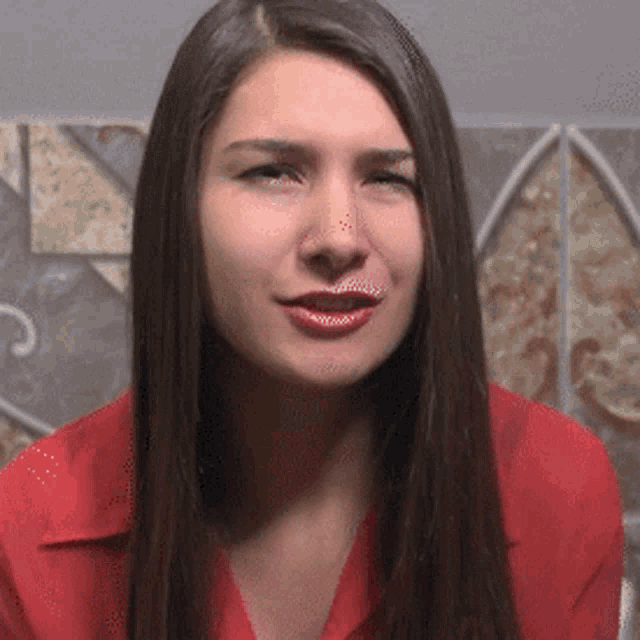 a woman with long hair is wearing a red shirt and smiling
