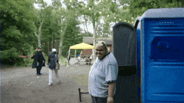 a man is standing in front of a blue toilet