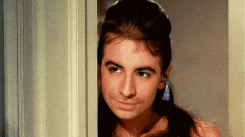 a woman is peeking out of a doorway and making a funny face