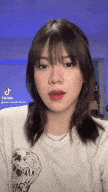 the girl is wearing a white t-shirt with a skull on it and a necklace .