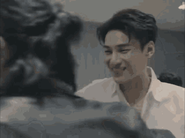 a man in a white shirt is smiling while talking to another man .